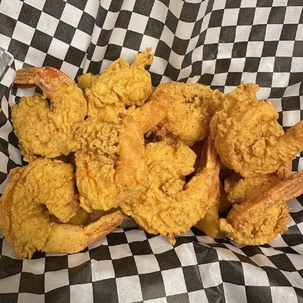 Golden-brown fried shrimp from Soul Goode, served in a basket lined with black and white checkered paper.