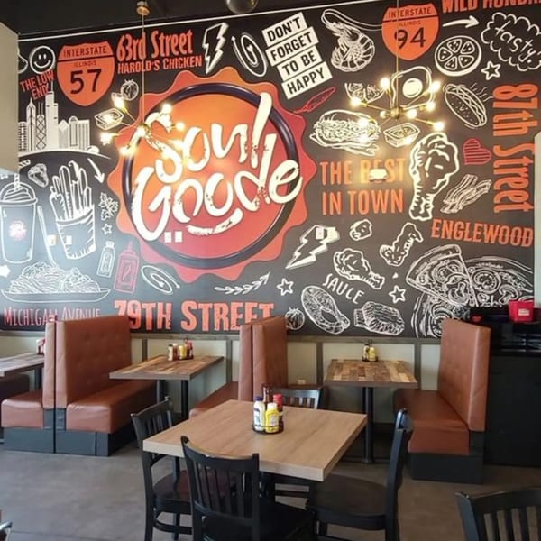 Soul Goode restaurant interior with booths, tables, and a large mural featuring food illustrations and street names.