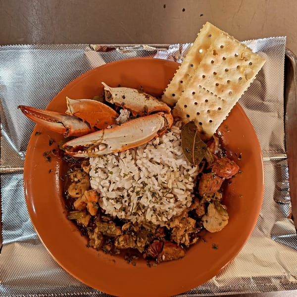 Soul Goode's seafood gumbo with crab claws, rice, and crackers on an orange plate.
