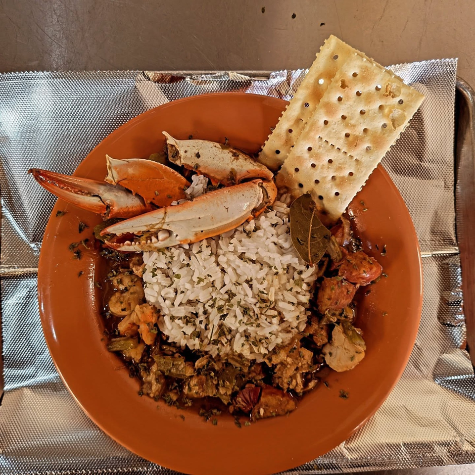 Soul Goode's seafood gumbo with crab claws, rice, and crackers on an orange plate.