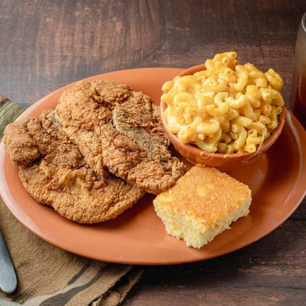 Soul Goode's fried chicken, macaroni and cheese, and cornbread on a rustic wooden table.